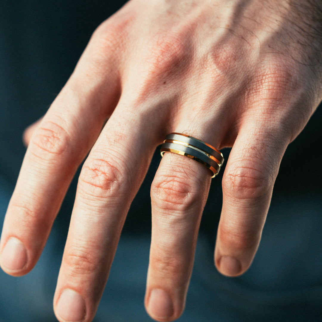 Close-up of a hand wearing a gold ring with a blurred background