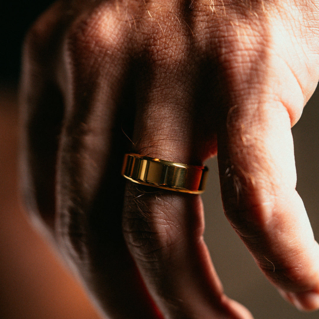 Gold ring on a person's finger with a dark background