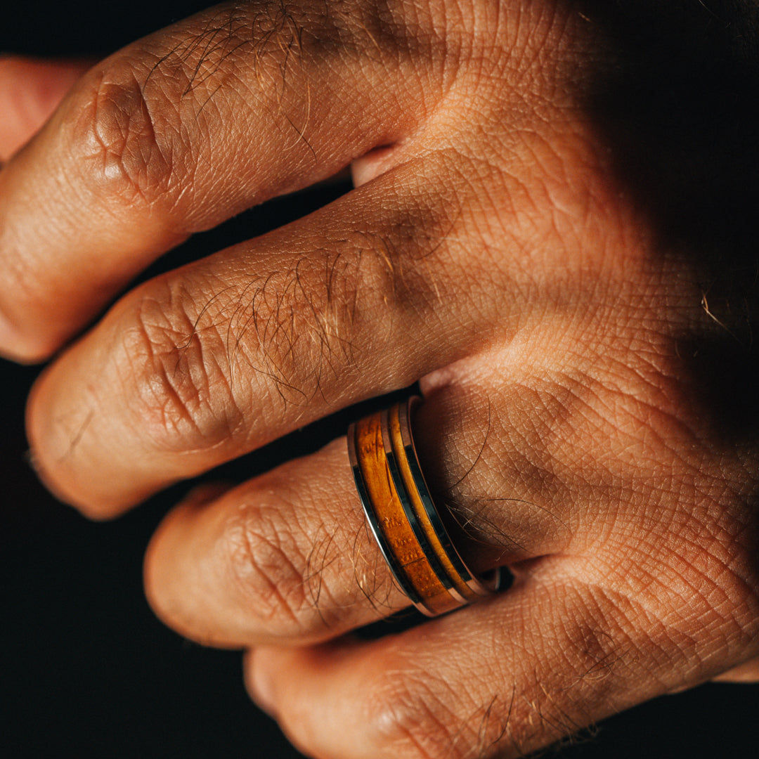 Close-up of a hand wearing a ring with a dark background