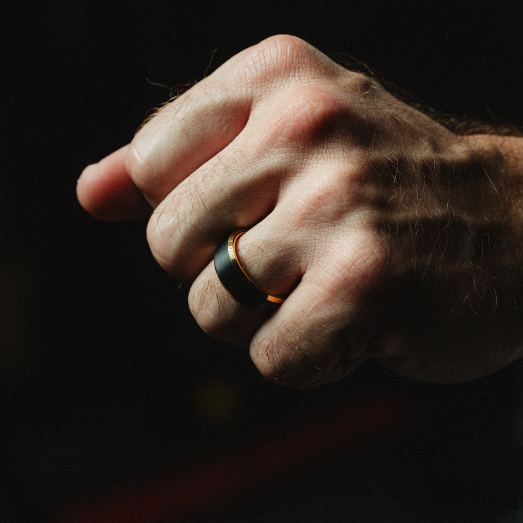 Hand wearing a ring on a dark background