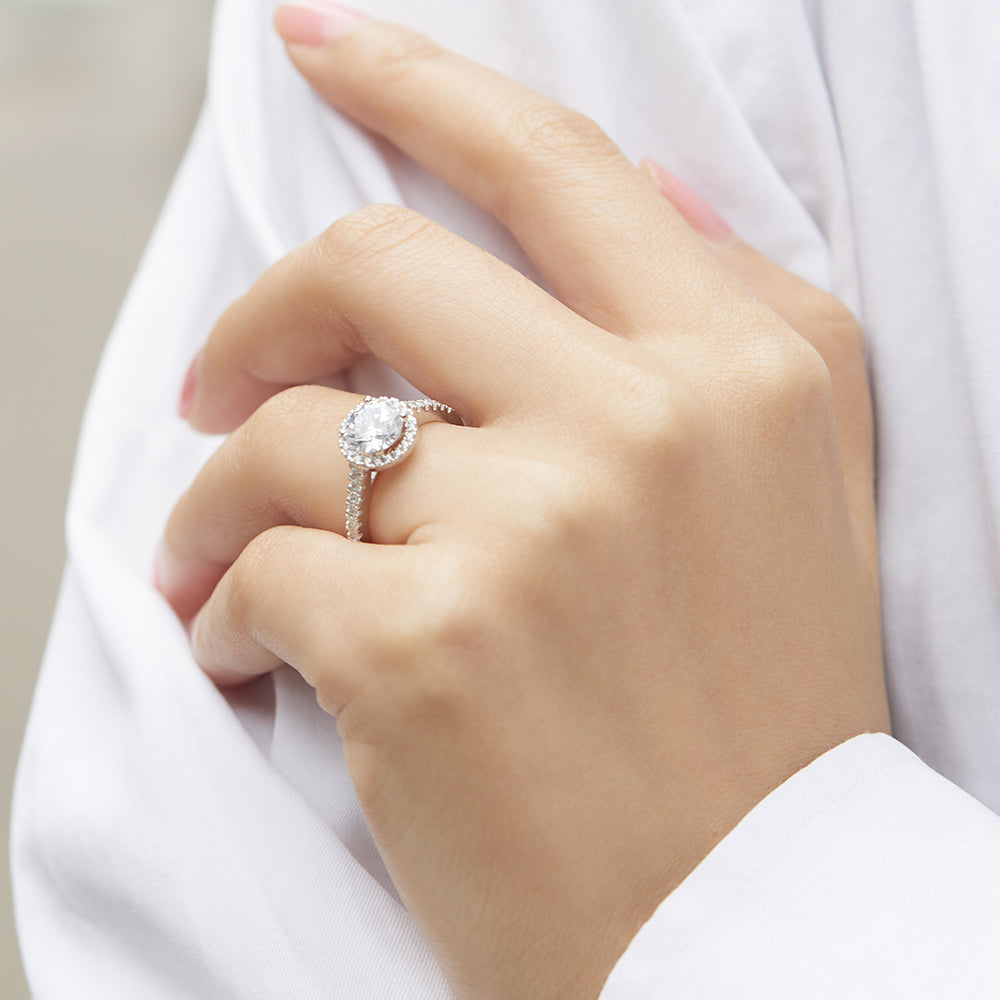 Close-up of a hand wearing a diamond ring with a blurred background
