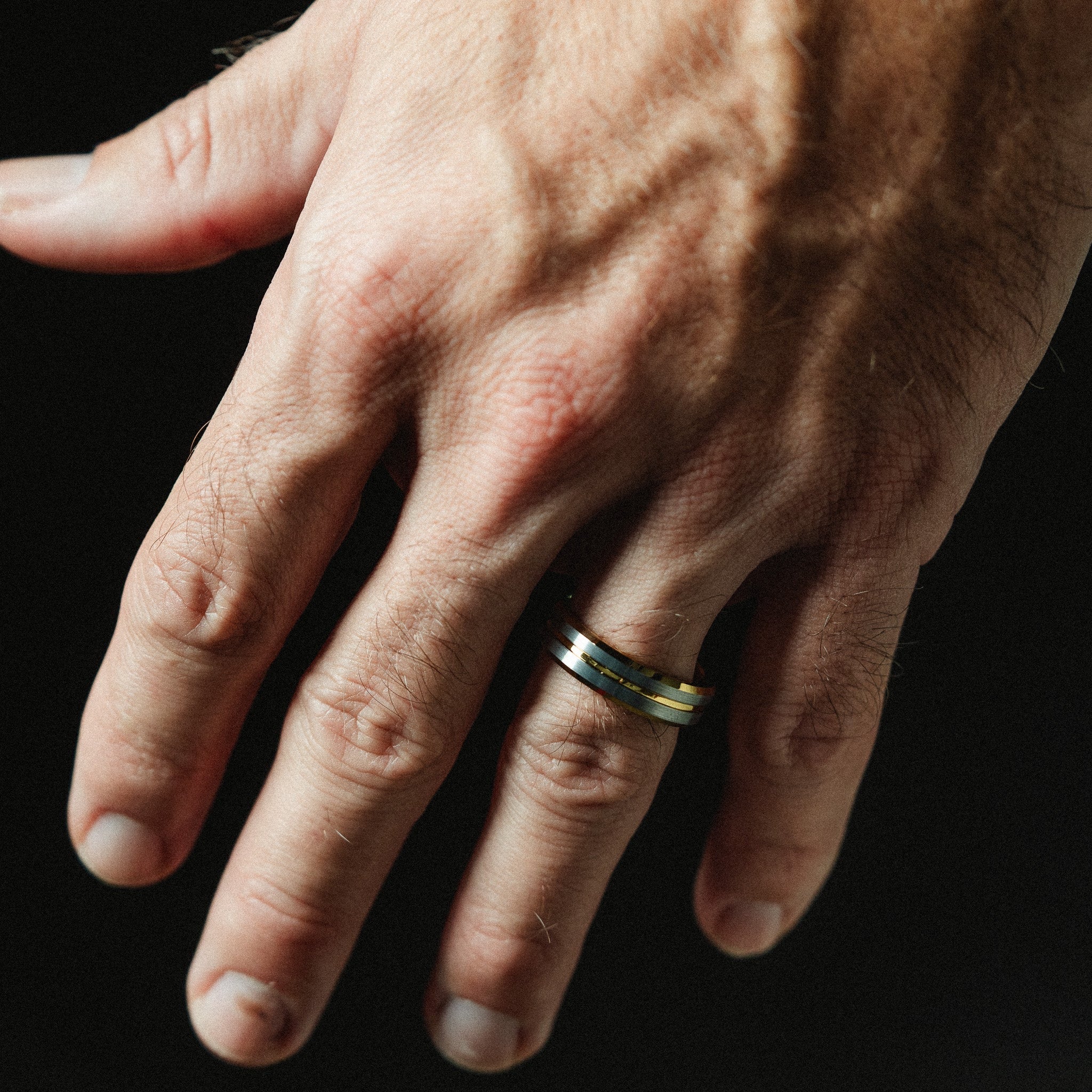 Hand with a gold ring on a black background