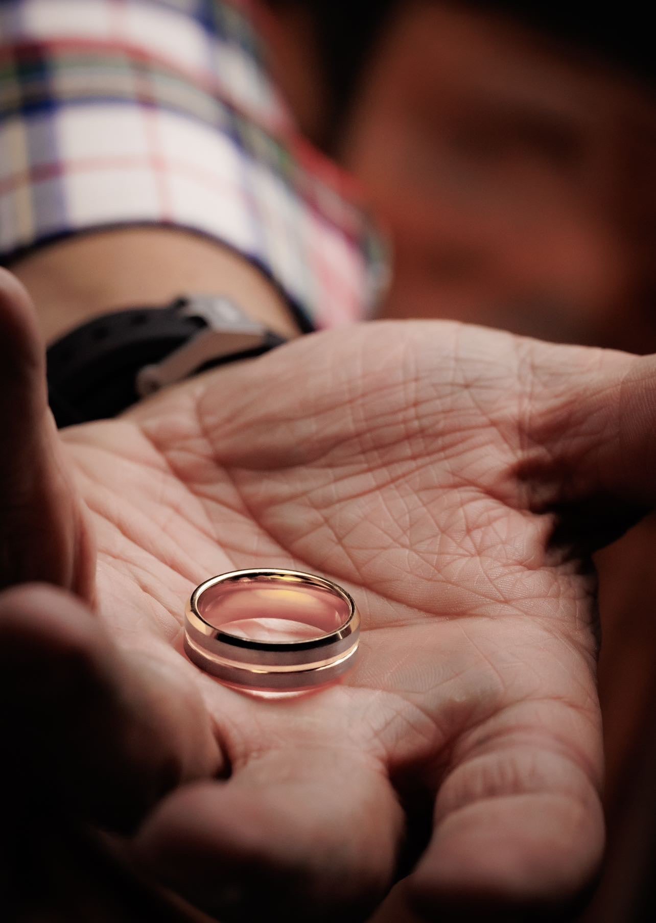 Gold ring held in a person's hand with a blurred background