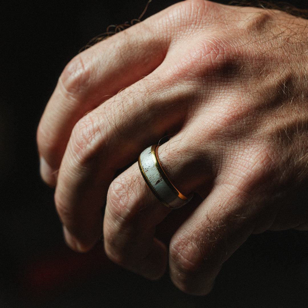 Close-up of a hand wearing a ring with a dark background
