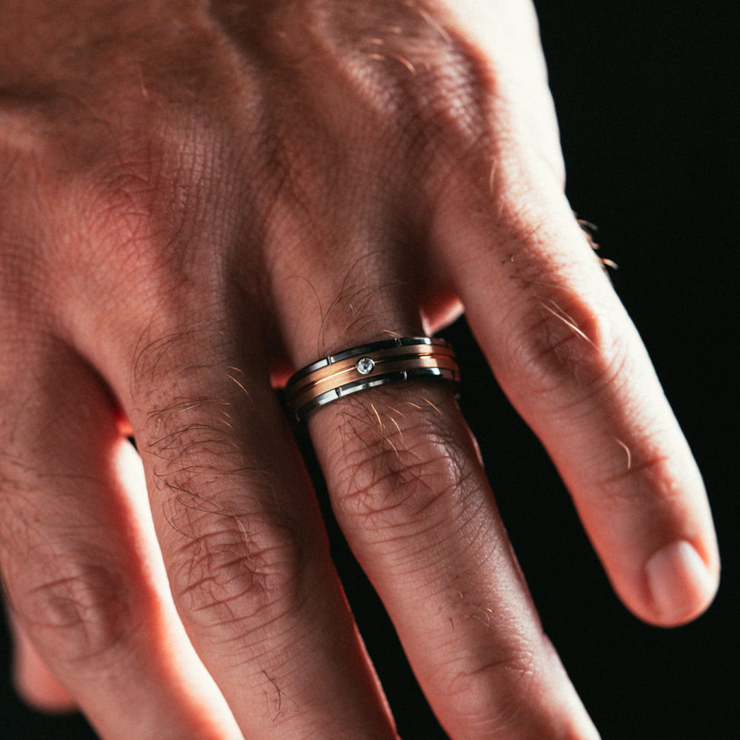 Close-up of a hand wearing two rings on a black background