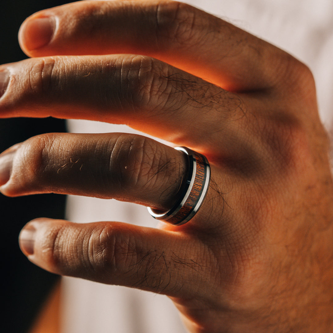 Hand wearing a wooden ring with a blurred background