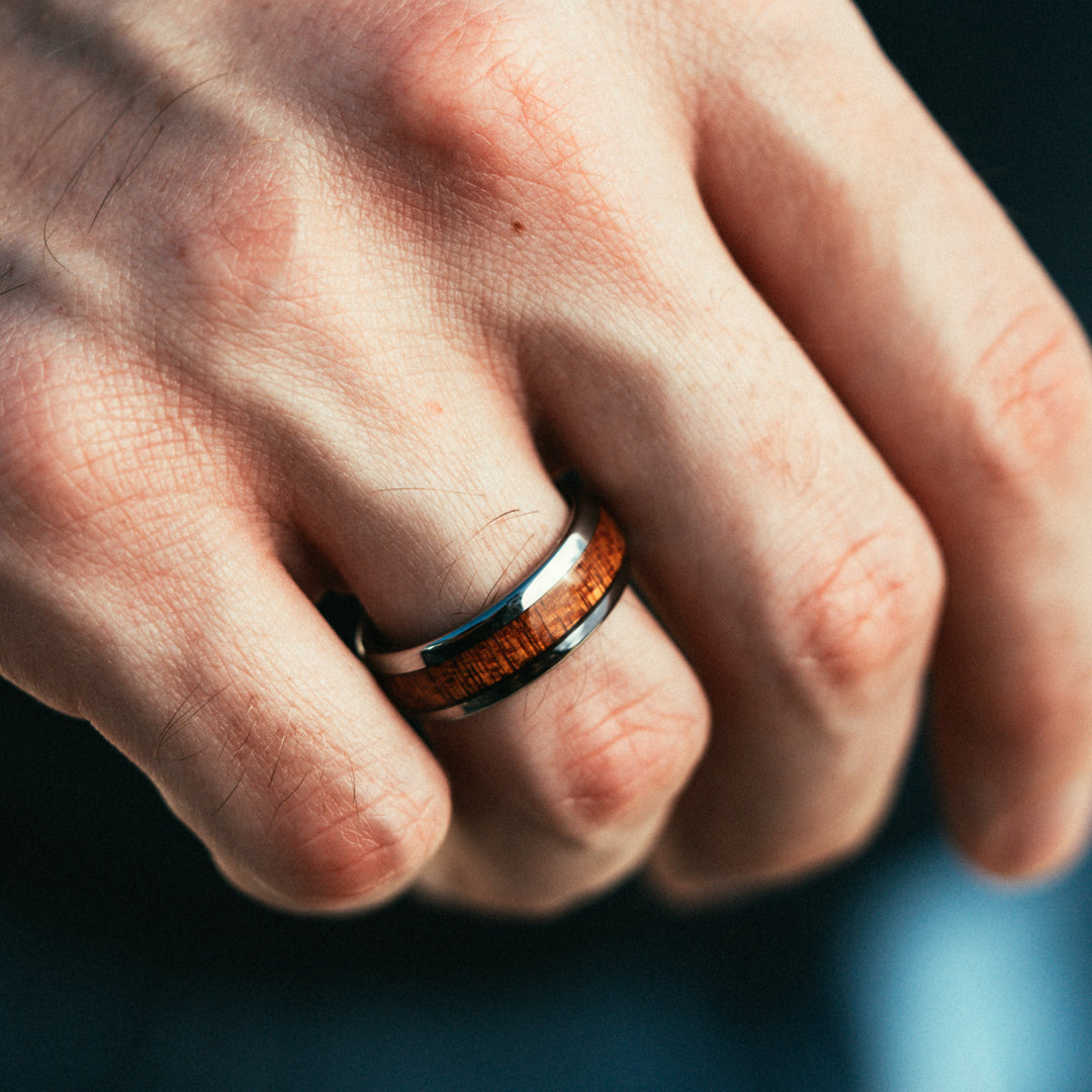 Close-up of a hand wearing a wooden ring with a blurred background