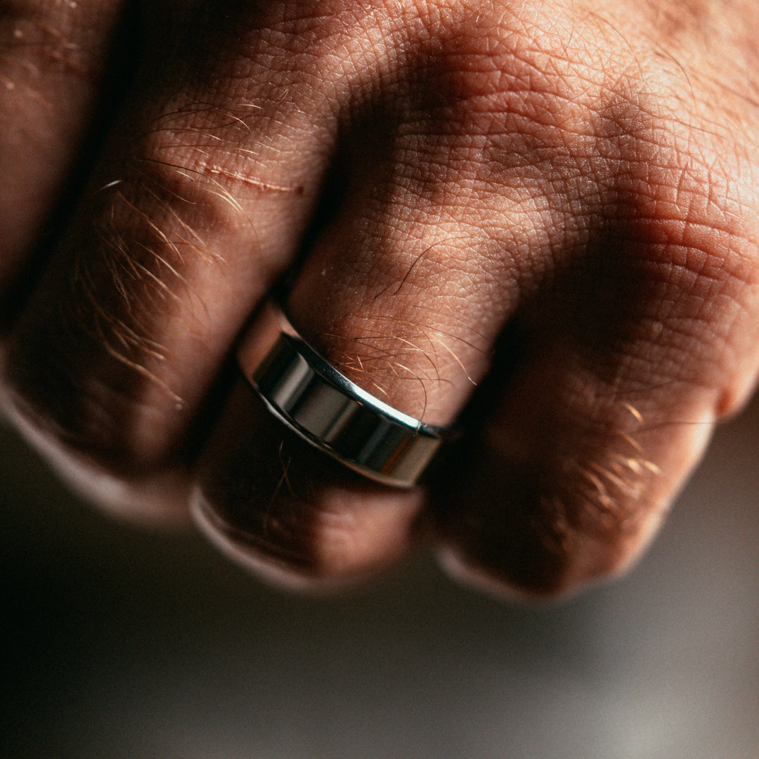 Close-up of a hand wearing a silver ring on a blurred background
