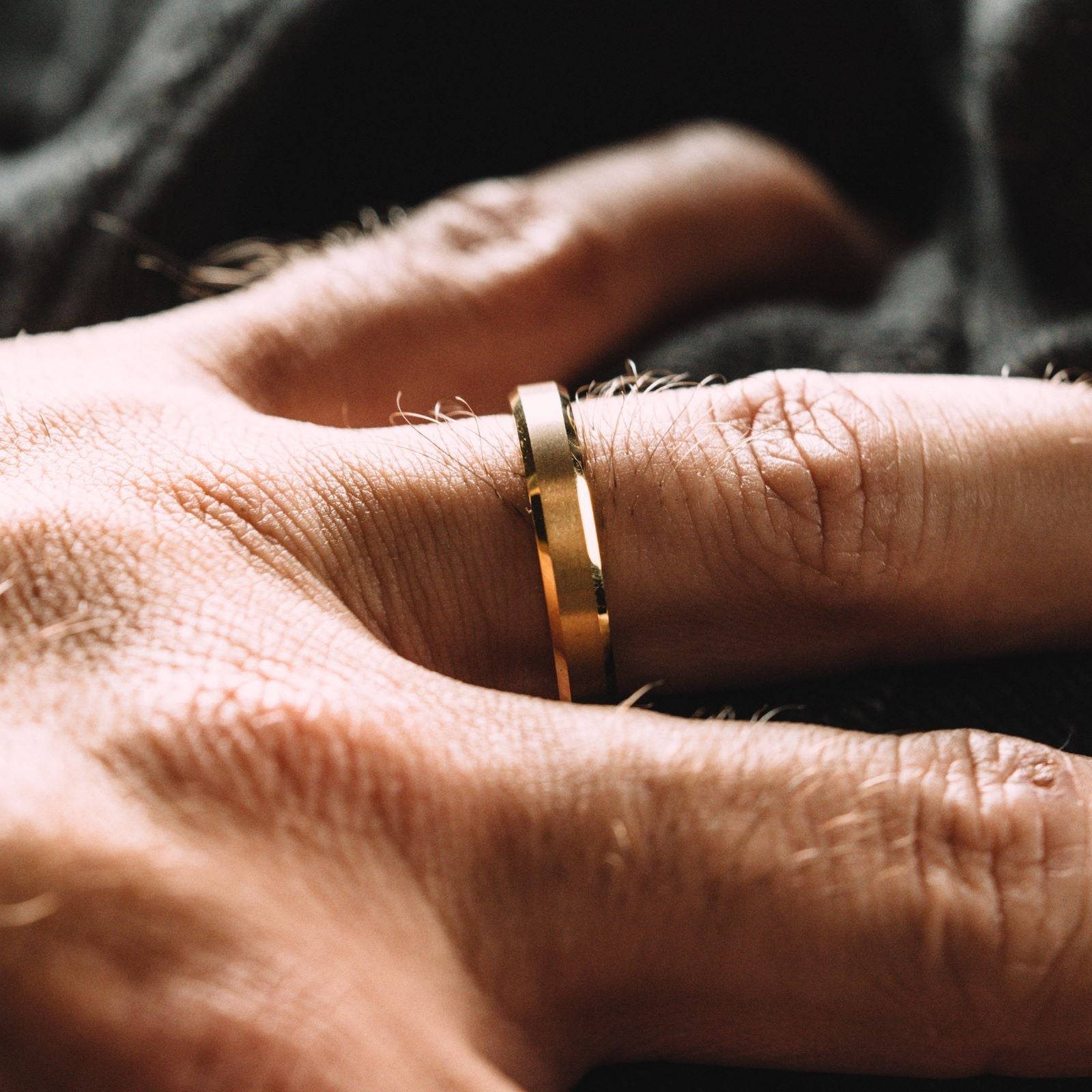 Close-up of a hand wearing a gold ring with a blurred background