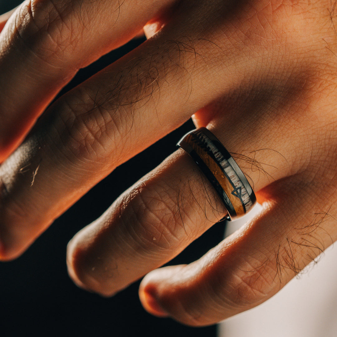 Close-up of a hand wearing a ring with a scenic design.