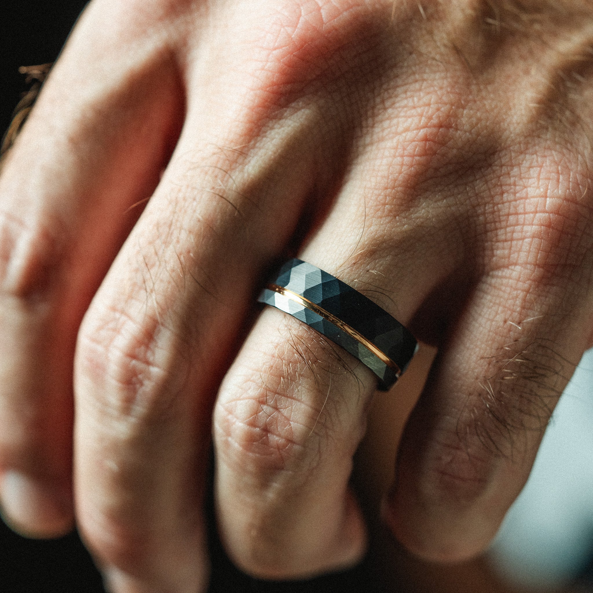 Close-up of a hand wearing a geometric-patterned ring.