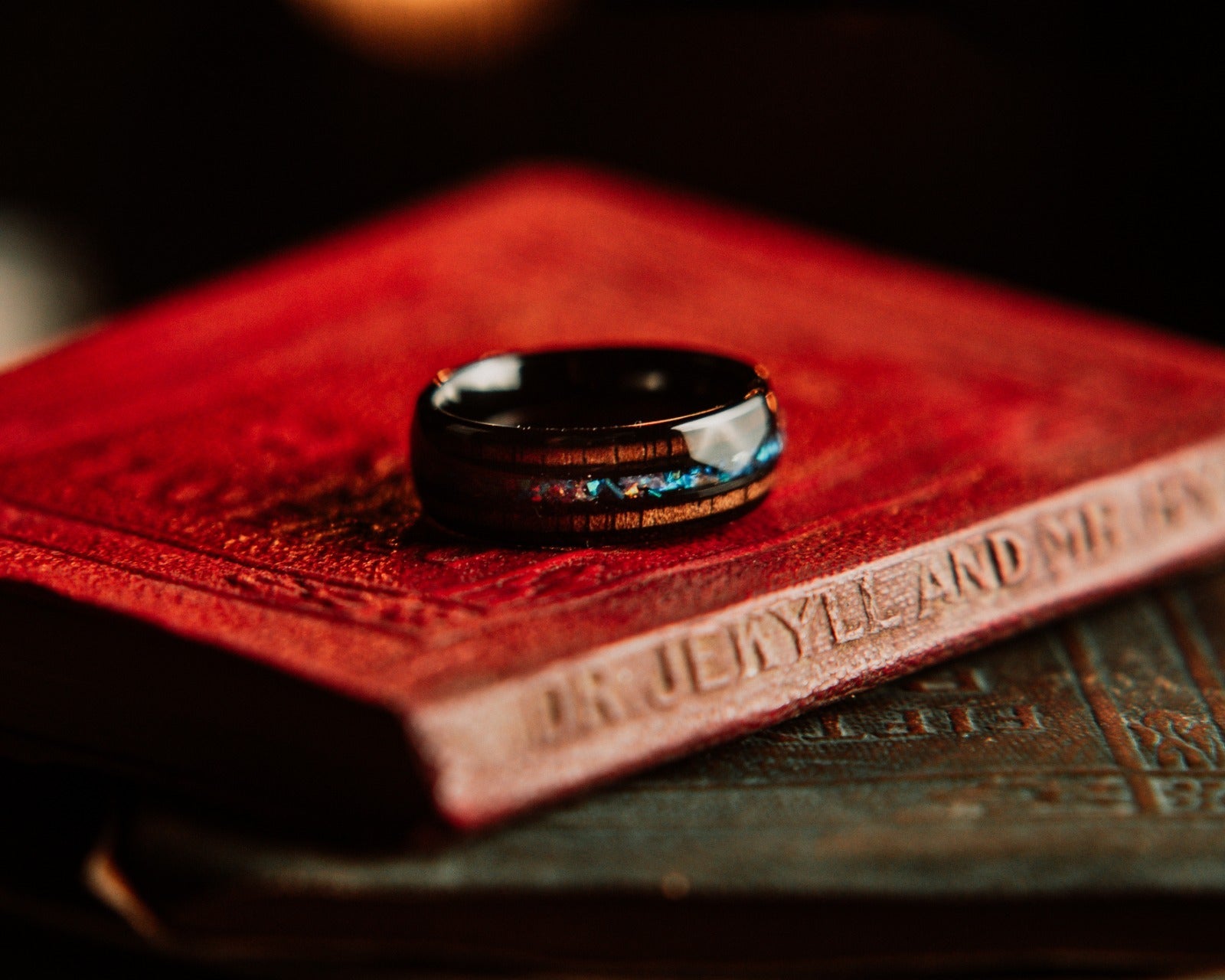 Black ring with blue accents on a red leather surface